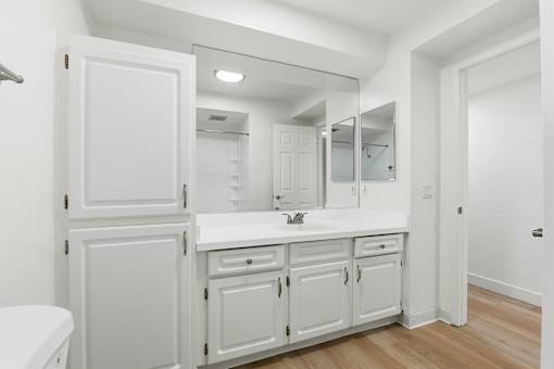 A white bathroom with a toilet, sink, and mirror.