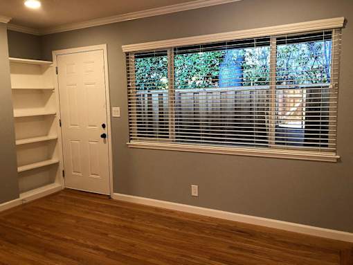 A room with a white door and a window with blinds.