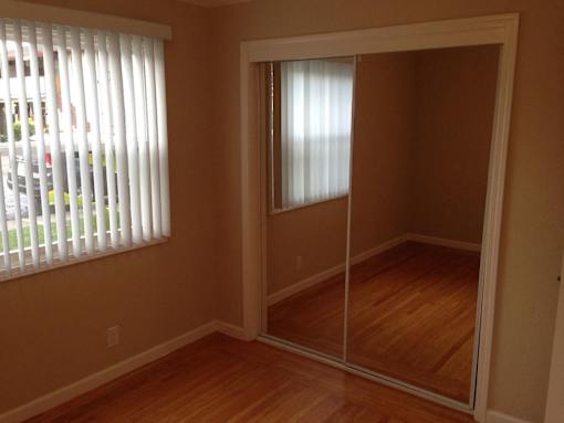 A room with a sliding door and a window with blinds.