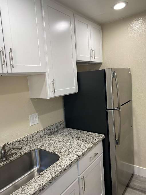 A kitchen with a black refrigerator and white cabinets.