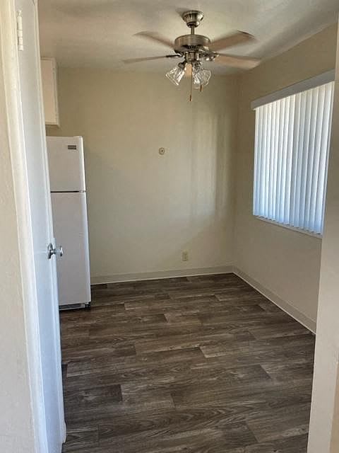 A room with a ceiling fan and a white refrigerator.