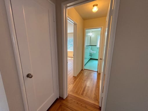 a bedroom and a hallway with a door open to a bathroom