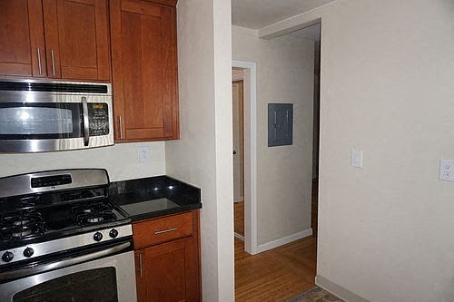 A kitchen with wooden cabinets and a stainless steel stove top oven.
