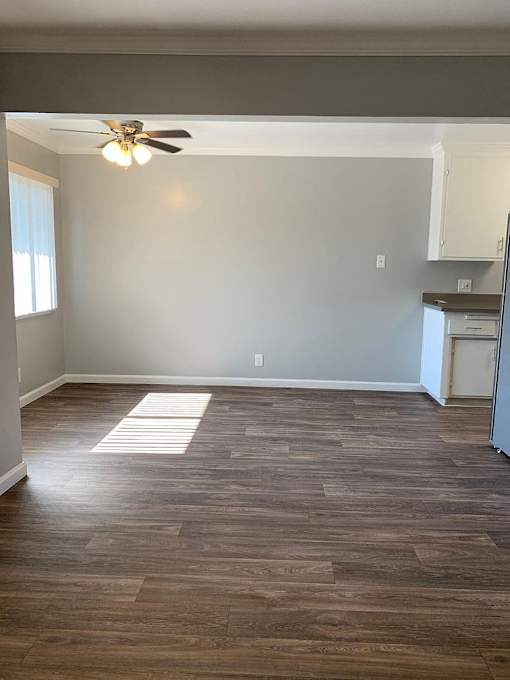 A room with a ceiling fan and wooden flooring.