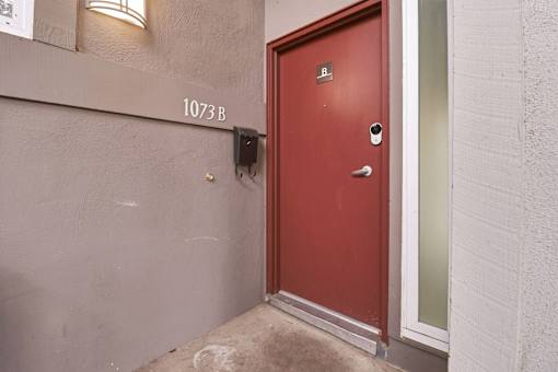 A red door with a black mailbox is on the side of a building.