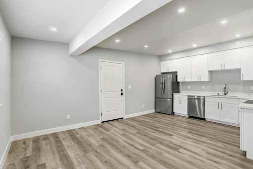 A kitchen with white cabinets and a wooden floor.