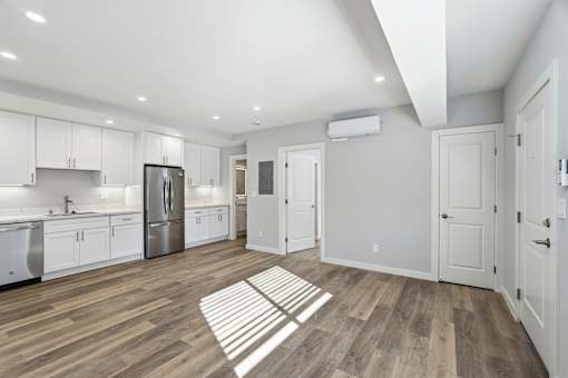 A kitchen with white cabinets and a wooden floor.