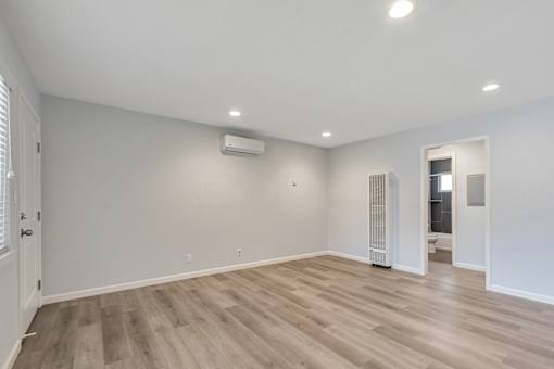 A spacious room with wooden flooring and white walls.