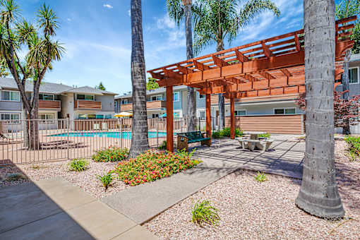 A patio area with a pool and a wooden pergola.