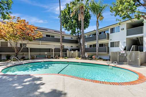 A swimming pool surrounded by trees and apartment buildings.