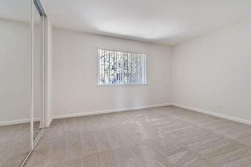 A room with a carpeted floor and a window with blinds.