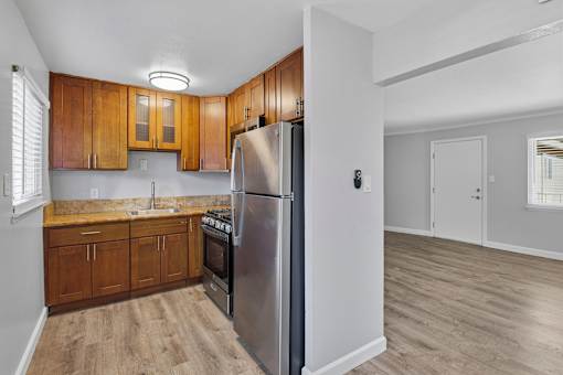 A kitchen with wooden cabinets and a stainless steel refrigerator.
