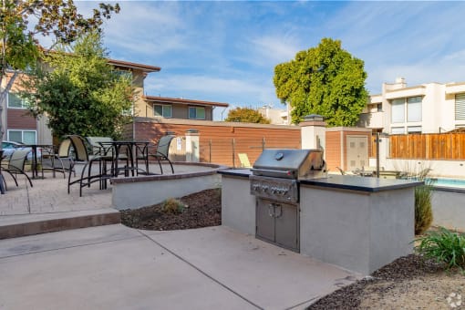 a backyard with a barbecue grill and a patio with tables and chairs
