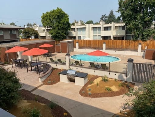 a pool and tables with umbrellas in an apartment yard