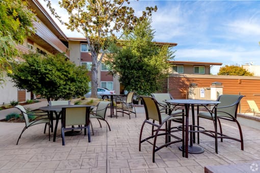 an outdoor patio with tables and chairs and trees