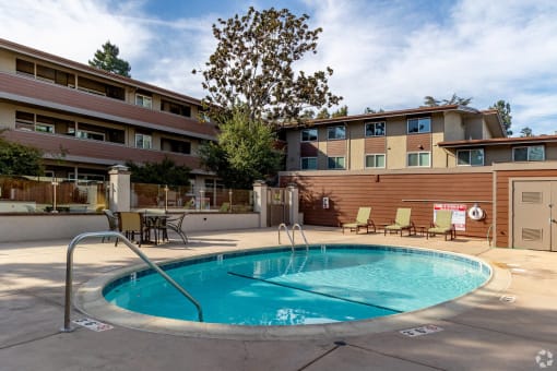 a swimming pool in front of a hotel with a building in the background