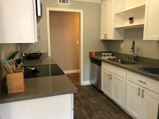 A kitchen with white cabinets and a black counter top.