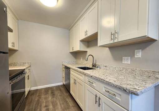 A kitchen with white cabinets and a granite countertop.