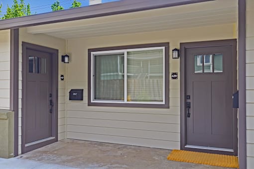 A house with a brown door and a window with white curtains.