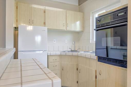 A kitchen with a white fridge and wooden cabinets.