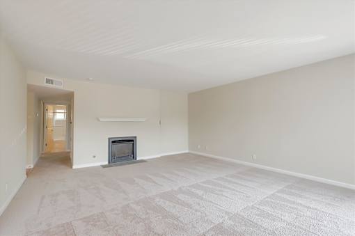 A living room with a fireplace and carpeted floor.
