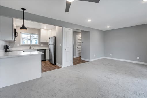 an empty living room and kitchen with a refrigerator and a sink