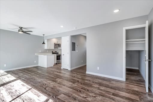 a living room with a kitchen and a ceiling fan