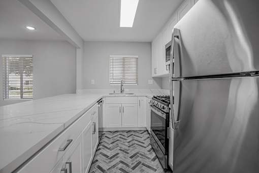 A black and white photo of a kitchen with a refrigerator on the right.