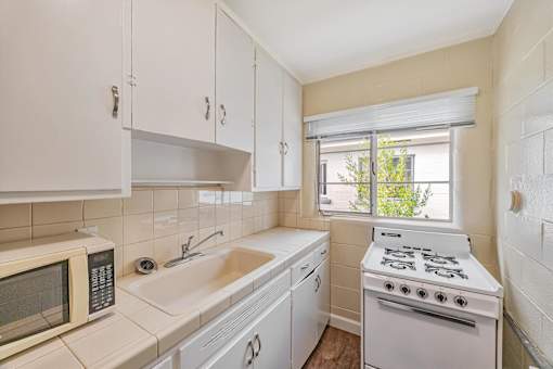 A kitchen with a white stove, sink, and microwave.