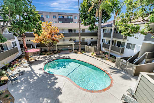 A swimming pool in a courtyard surrounded by trees and buildings.