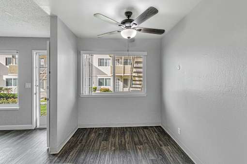 A room with a ceiling fan and a window overlooking a building.