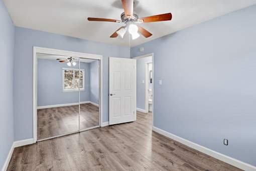 A room with a ceiling fan and a sliding glass door.