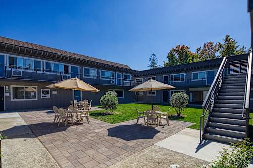 a patio with tables and umbrellas in front of a building