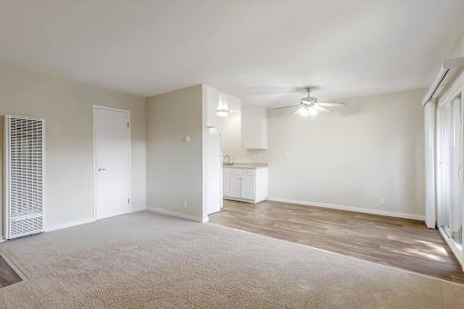 A spacious living room with a carpeted floor and a ceiling fan.