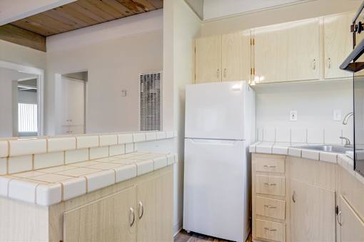 A white refrigerator is in a kitchen with wooden cabinets.