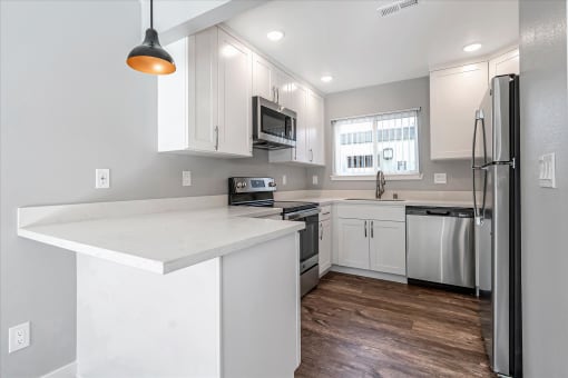 a white kitchen with stainless steel appliances and a counter top