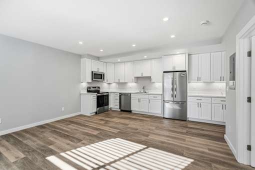 A kitchen with white cabinets and a wooden floor.