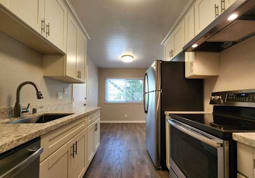 A kitchen with a black refrigerator and stove top oven.
