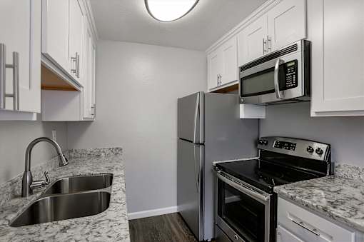 A kitchen with a sink, refrigerator, and stove.