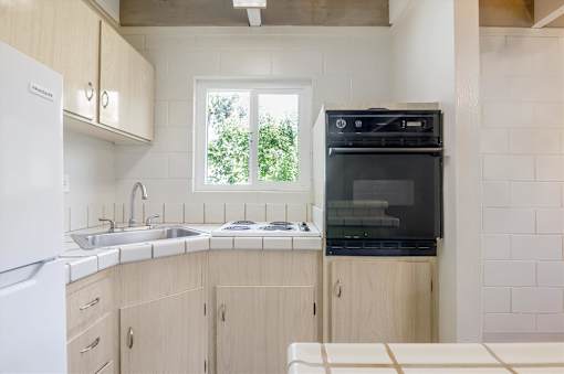 A kitchen with a white fridge, black oven and wooden cabinets.