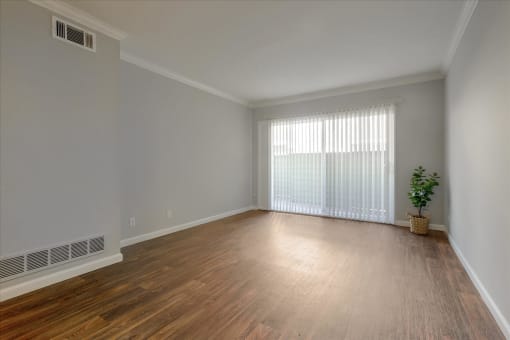 A room with wooden floors and a window with blinds.