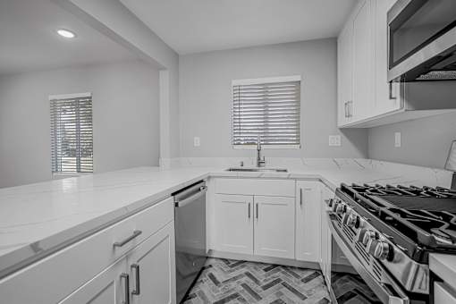A modern kitchen with white cabinets and a black stove top.
