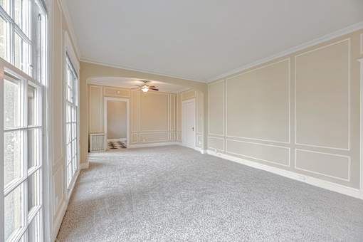 A large, empty room with white walls and carpeted floor.