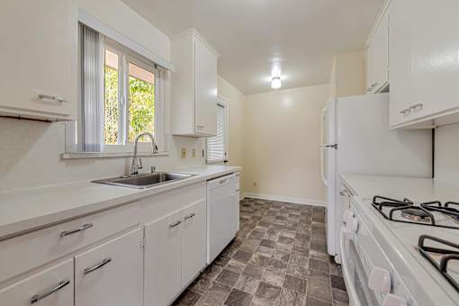 A kitchen with white cabinets and a tiled floor.