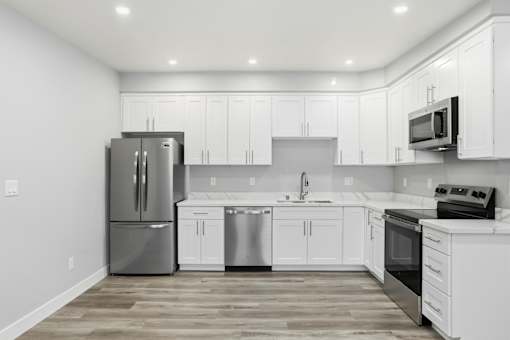 A modern kitchen with white cabinets and stainless steel appliances.