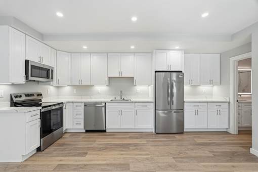 A modern kitchen with white cabinets and stainless steel appliances.