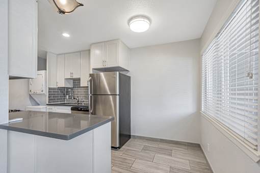 A modern kitchen with a stainless steel refrigerator and white cabinets.