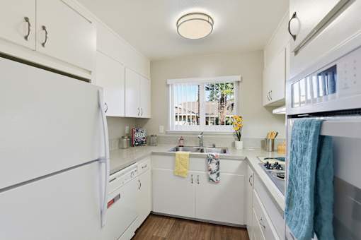 A white kitchen with a refrigerator on the left and a microwave on the right.