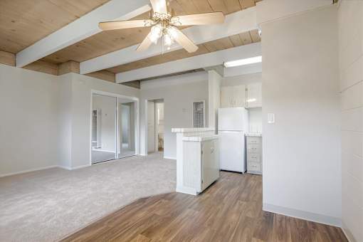 A kitchen with white appliances and wooden floors.