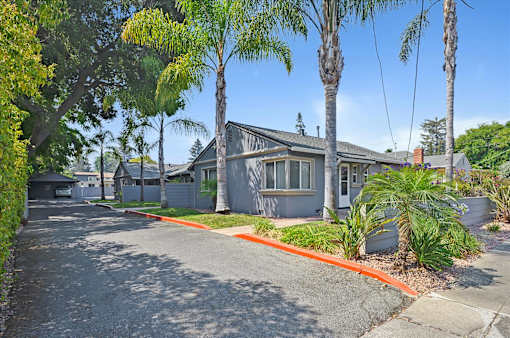 A building with a driveway and trees in front.